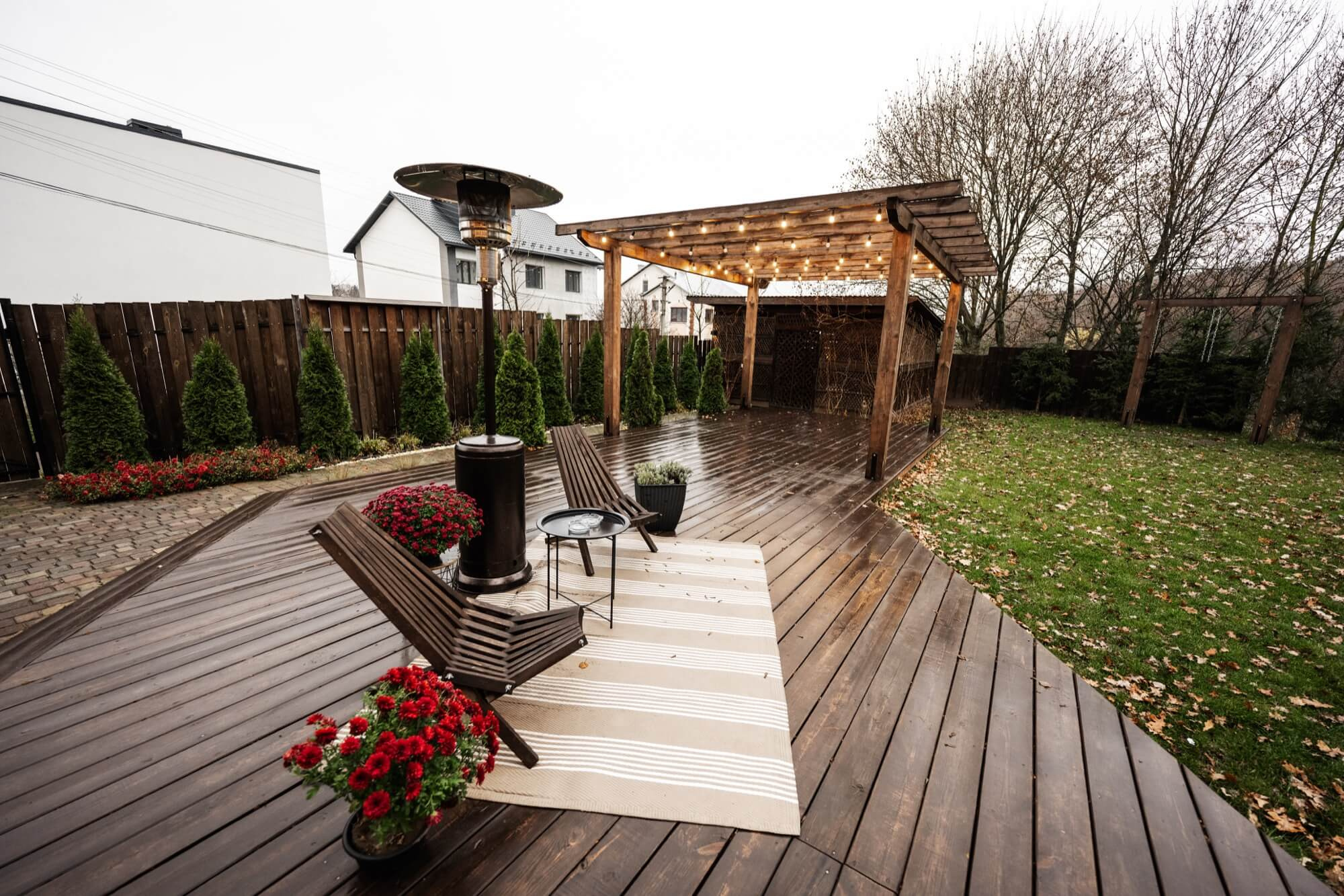Altan med pergola, slingrande belysning och regnblank trall.